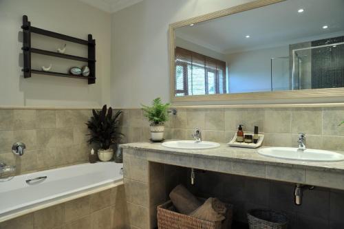 a bathroom with two sinks and a bath tub at Claires of Sandton Luxury Guest House in Johannesburg