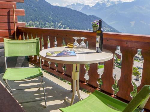 a table and chairs on a balcony with a bottle of wine at Apartment Pinot Gris combles by Interhome in Verbier