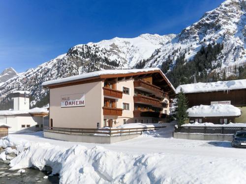 a building in the snow with mountains in the background at Apartment Daheim – Edelweiß by Interhome in Plangeross