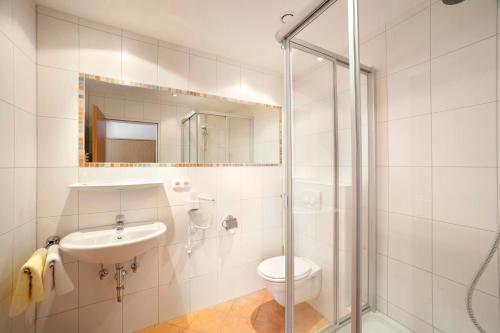 a bathroom with a toilet and a sink and a shower at Kurhotel Luitpold in Bad Wörishofen