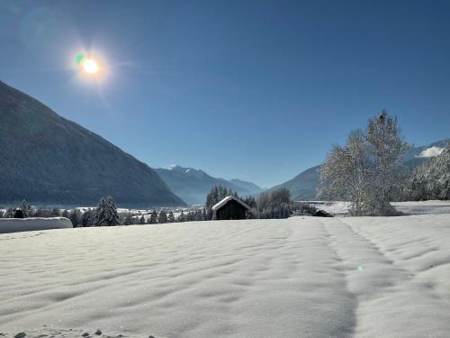 a snow covered field with a house in the background at Apartment Christina by Interhome in Tarrenz