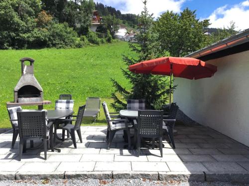 eine Terrasse mit einem Tisch, Stühlen und einem Sonnenschirm in der Unterkunft Chalet Jagdhaus Biedenegg - FIE215 by Interhome in Fliess