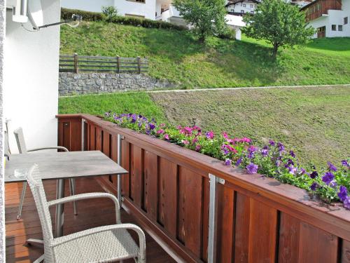 a wooden deck with a table and chairs and flowers at Apartment Alpenherz - PTZ431 by Interhome in Fendels