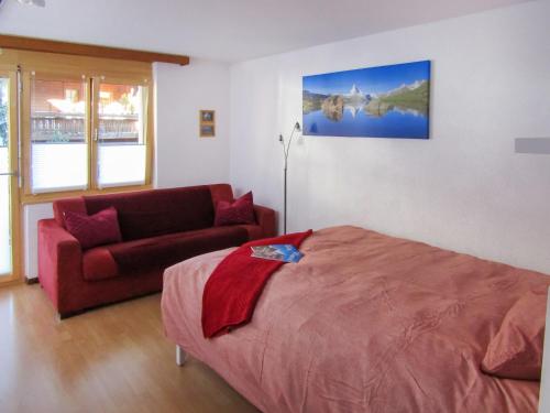1 dormitorio con cama roja y sofá en Apartment Sungold-1 by Interhome en Zermatt