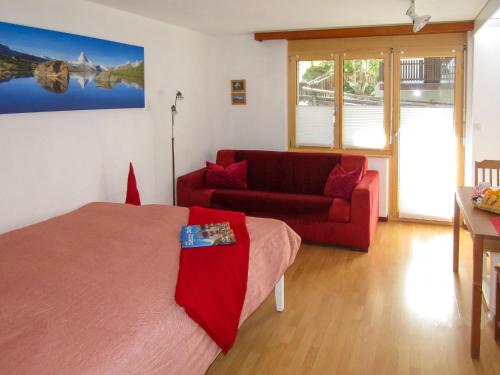 uma sala de estar com uma cama vermelha e um sofá em Apartment Sungold-2 by Interhome em Zermatt