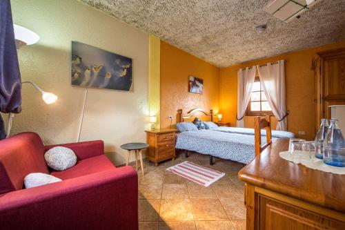ein Schlafzimmer mit einem Bett und einem roten Sofa in der Unterkunft Casa Tenerife in San Juan de la Rambla