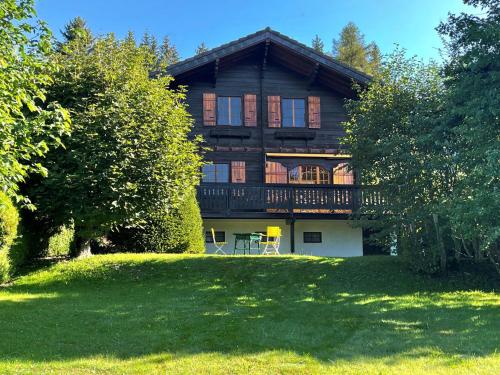 a large wooden house with a lawn in front of it at Chalet Chalet Merymont by Interhome in Villars-sur-Ollon