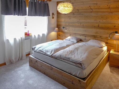 1 dormitorio con 1 cama grande y pared de madera en Apartment La Joie by Interhome, en Crans-Montana