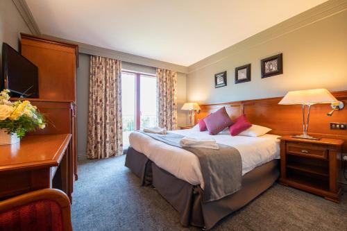 Habitación de hotel con cama grande y escritorio. en Bryn Meadows Golf, Hotel & Spa, en Blackwood