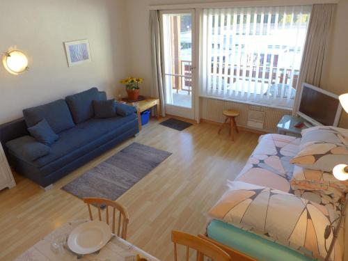 Una sala de estar con un sofá azul y una mesa. en Apartment Farinet B 13 by Interhome, en Crans-Montana