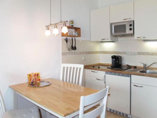 eine Küche mit einem Holztisch und weißen Schränken in der Unterkunft Apartment Ostsee-Residenz - DMP173 by Interhome in Damp