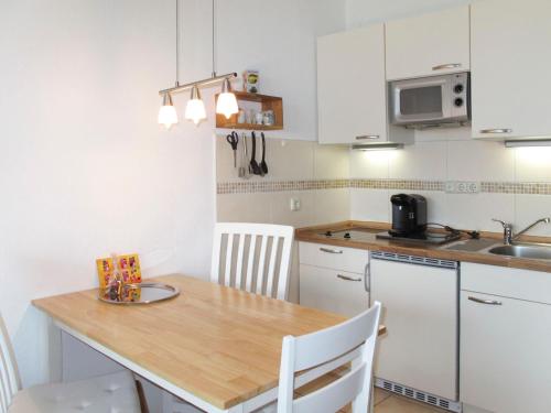 a kitchen with a wooden table and white cabinets at Apartment Ostsee-Residenz - DMP173 by Interhome in Damp