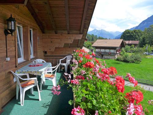 una mesa y sillas en el porche de una cabaña con flores en Apartment Oltschiblick by Interhome, en Brienzwiler