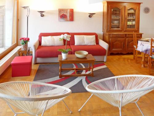 a living room with a red couch and two chairs at Apartment Terrasse Des Alpes 708 by Interhome in Vermala