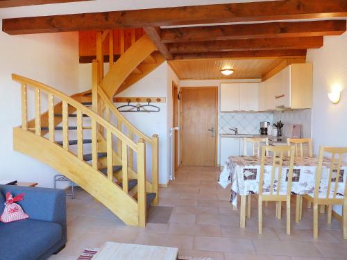 ein Wohnzimmer mit einer Treppe, einem Tisch und einer Küche in der Unterkunft Apartment Ermitage 13 by Interhome in Villars-sur-Ollon