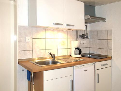 a kitchen with a sink and white cabinets at Apartment Osterende-2 by Interhome in Süderwisch