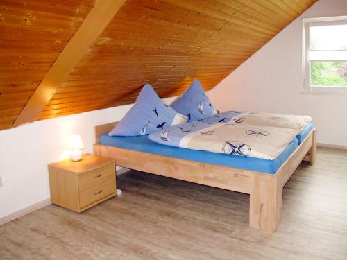 ein Schlafzimmer mit einem Bett mit blauen Kissen und einer Holzdecke in der Unterkunft Apartment Gronau by Interhome in Otterndorf