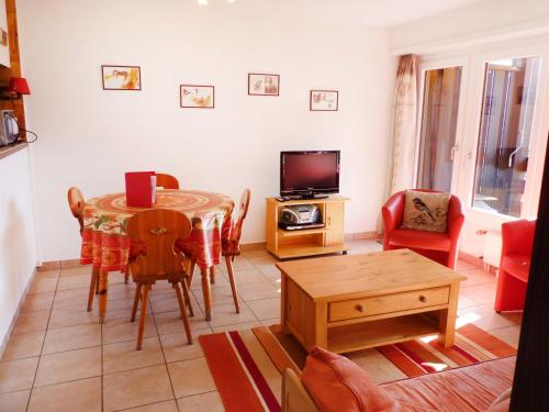 ein Wohnzimmer mit einem Tisch und einem TV in der Unterkunft Apartment Centaure B RS 2 by Interhome in Ovronnaz