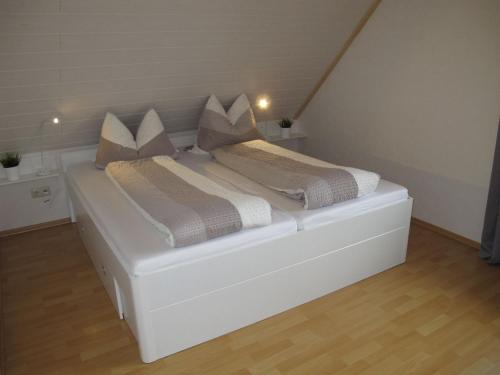 a white bed with pillows on it in a room at Apartment Rosenboom by Interhome in Wiarden