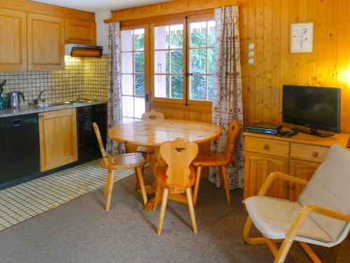 eine Küche mit einem Holztisch mit Stühlen und einem TV in der Unterkunft Apartment Le Brévent 4 by Interhome in Villars-sur-Ollon