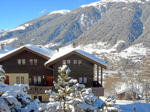 a house covered in snow with mountains in the background at Apartment Aragon B47 by Interhome in Ernen