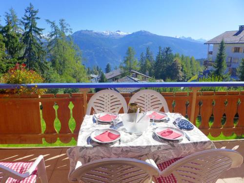 una mesa con 4 sillas en un balcón con montañas en Apartment Le Chalet by Interhome en Crans-Montana