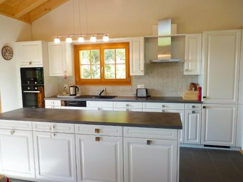 Una cocina blanca con gabinetes blancos y un fregadero. en Chalet Helene by Interhome, en Ovronnaz