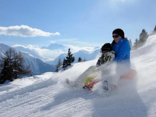 two people are riding down a snow covered slope at Apartment Aragon M86 by Interhome in Fiesch
