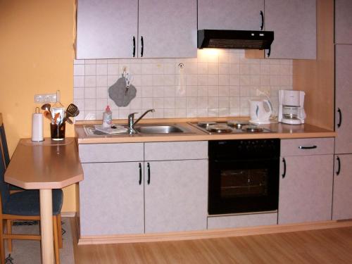 a kitchen with white cabinets and a sink and a stove at Apartment Ferienhof Peters-1 by Interhome in Funnixer Neue Mitteldeich