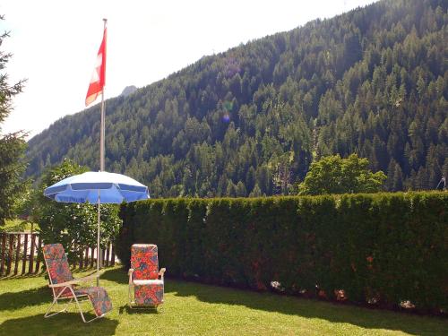 two chairs and an umbrella in a yard with a mountain at Apartment Verena by Interhome in Bedretto