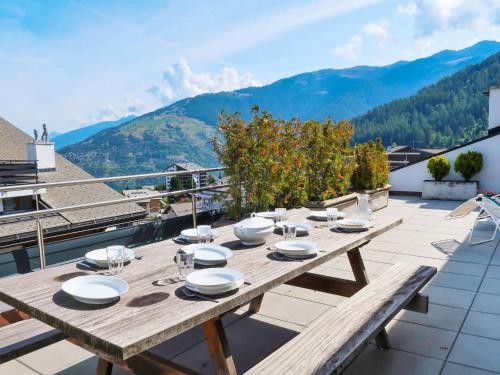 a wooden table on a roof with a view of mountains at Apartment Les Platanes I5 by Interhome in Nendaz