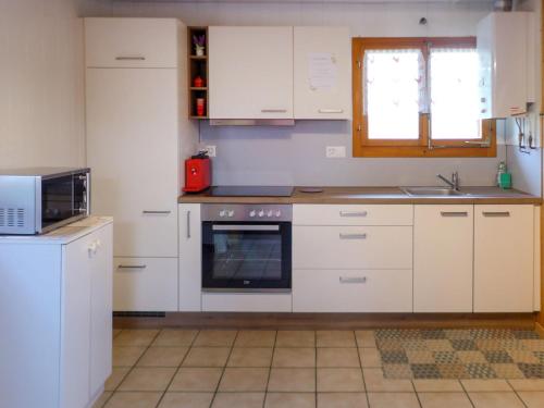 una cucina con armadi bianchi, lavandino e forno a microonde di Chalet Hügli by Interhome a Bure