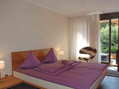 a bedroom with a bed with purple sheets and a window at Apartment Giardino by Interhome in Ascona
