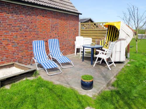 eine Terrasse mit Stühlen, einem Tisch und einem Zaun in der Unterkunft Holiday Home Osterkamp by Interhome in Friederikensiel