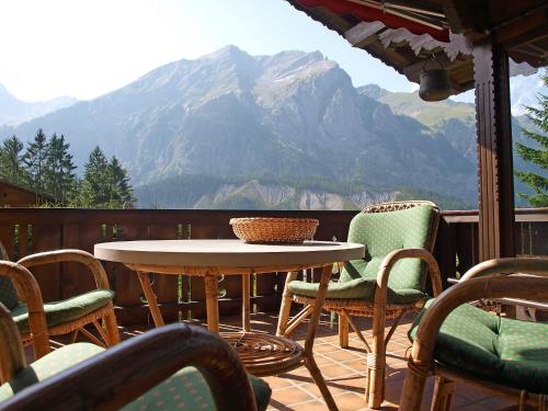 een tafel en stoelen op een balkon met een berg bij Holiday Home Chalet Marietta by Interhome in Kandersteg