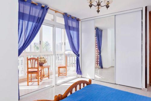 アロナにあるPlaya de las Americas aptのベッドルーム(青いカーテン、テーブル、椅子付)