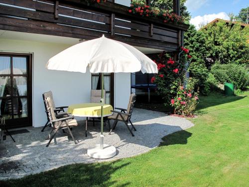 a table and chairs under an umbrella in a yard at Apartment Janik by Interhome in Bischofsmais