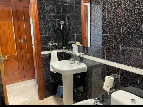 een zwart betegelde badkamer met een wastafel en een toilet bij Hostal Torresmancha in La Guardia