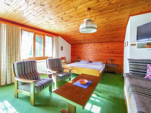 um quarto com uma cama, 2 cadeiras e uma mesa em Apartment Chalet Marie Rosa-1 by Interhome em Grindelwald