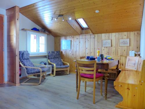 Zimmer mit Holzwänden, einem Tisch und Stühlen in der Unterkunft Apartment Chalet Seeberg by Interhome in Lenk im Simmental