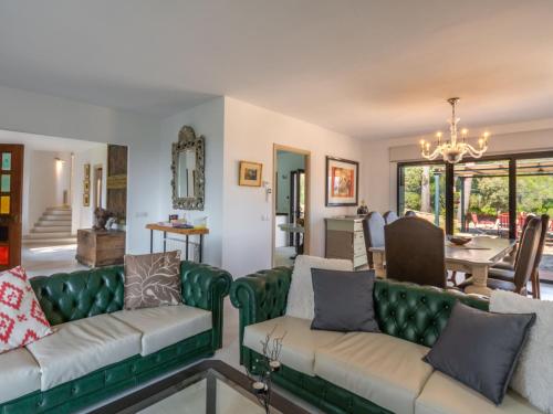 a living room with green couches and a dining room at Holiday Home S'Hort des Verger by Interhome in Esporles