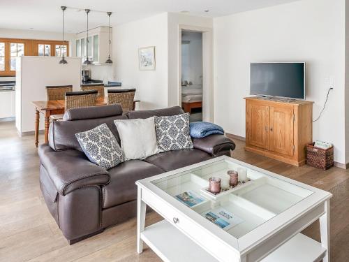 ein Wohnzimmer mit einem braunen Sofa und einem Tisch in der Unterkunft Apartment Chalet Smaragd-1 by Interhome in Grindelwald