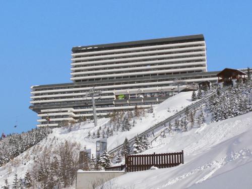 un grand bâtiment au sommet d'une montagne enneigée dans l'établissement Apartment Brelin-6 by Interhome, aux Menuires