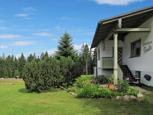 una casa blanca con porche y algunos arbustos y árboles en Holiday Home Paula by Interhome, en Bayerisch Eisenstein