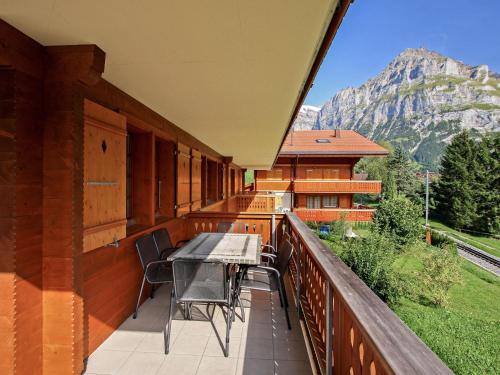 einen Balkon mit einem Tisch, Stühlen und einem Berg in der Unterkunft Apartment Chalet Eiger-1 by Interhome in Grindelwald