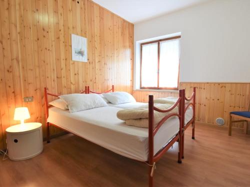 a bedroom with a bed with a wooden wall at Apartment Villa Martinelli-2 by Interhome in Crone