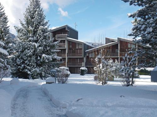 a building covered in snow with trees and a driveway at Apartment Les Joncioles by Interhome in Samoëns