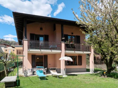 a house with chairs and an umbrella in the yard at Apartment Domenica - GRV150 by Interhome in Consiglio di Rumo