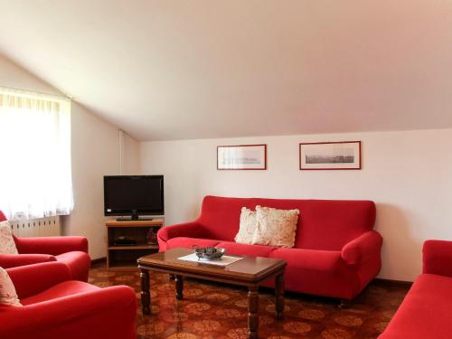 Apartment Casa Canali-2 by Interhome في ليدرو: غرفة معيشة مع أرائك حمراء وتلفزيون