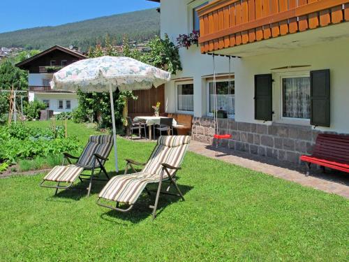 zwei Stühle und ein Regenschirm im Hof eines Hauses in der Unterkunft Apartment Demetz by Interhome in St. Ulrich in Gröden